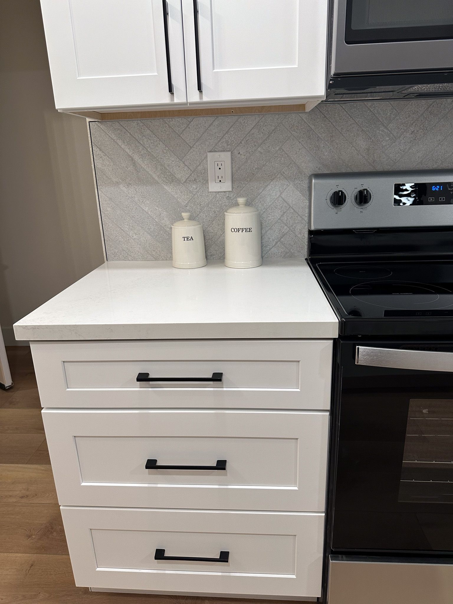 A kitchen with white cabinets and a black stove top oven.