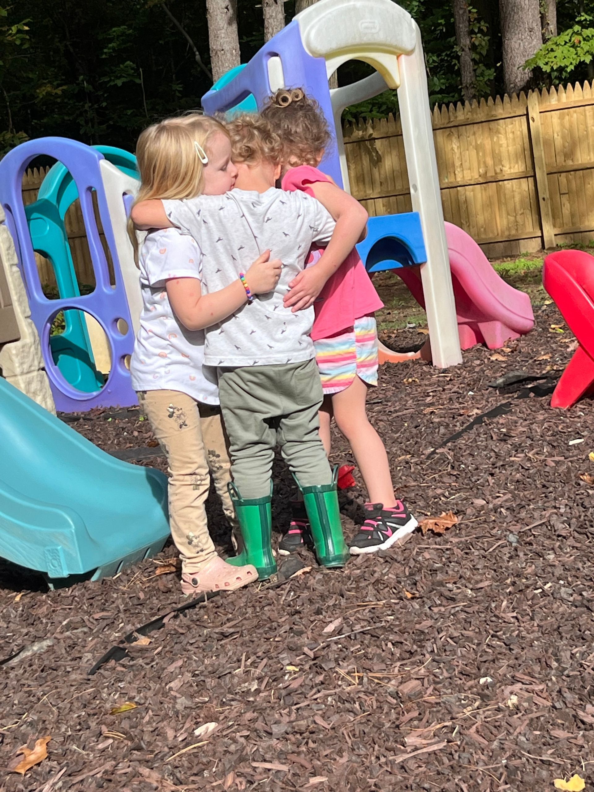A group of children are hugging each other in a playground.