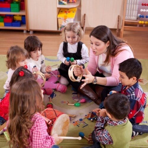 A group of children are sitting on the floor playing musical instruments