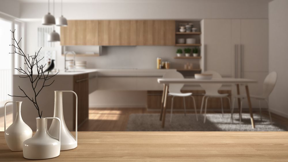 Uma mesa de madeira com vasos em frente a uma cozinha.