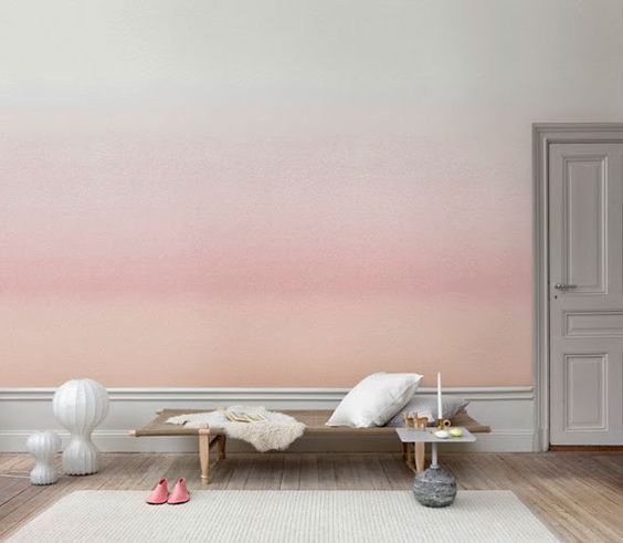 Uma sala de estar com uma parede rosa ombré e um banco