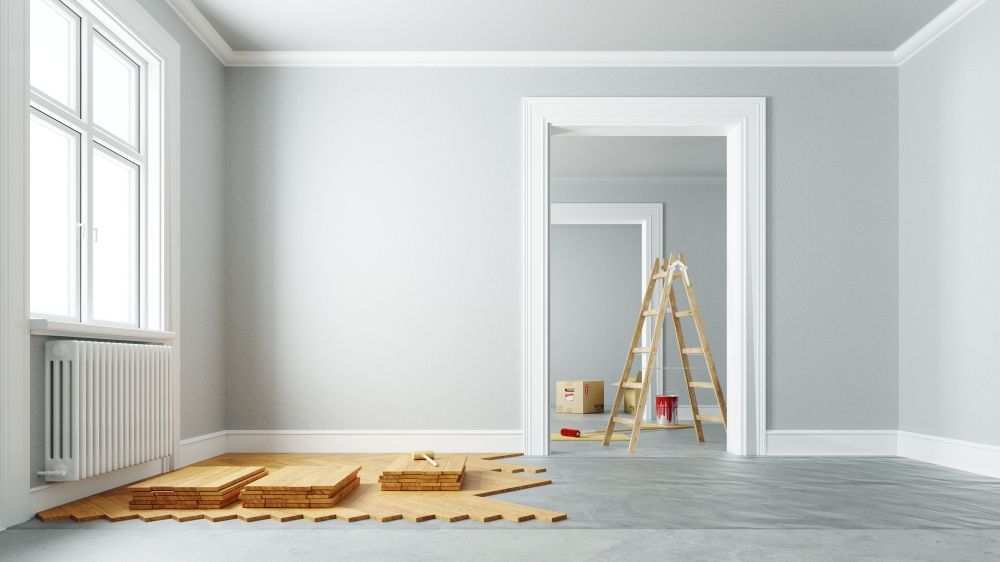 Uma sala vazia com piso de madeira e uma escada.