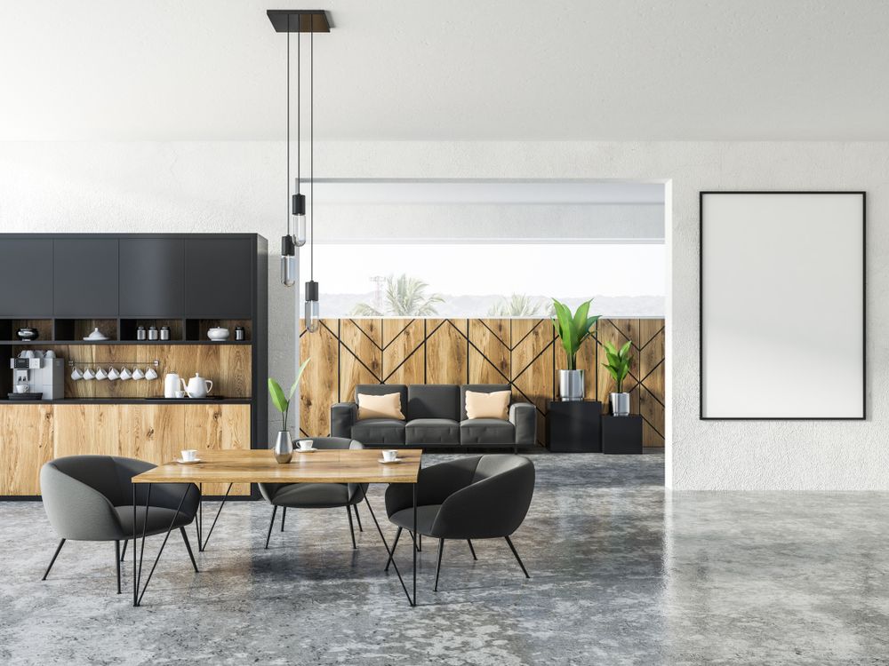 Uma sala de estar com um sofá, mesa, cadeiras e um pôster na parede.