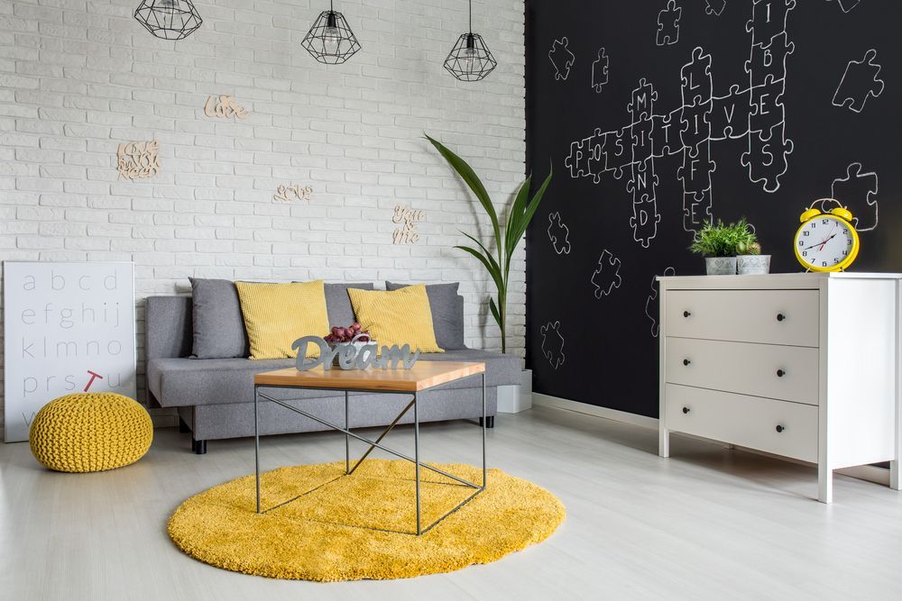 Uma sala de estar com um sofá, mesa de centro, cômoda e parede de quadro negro.