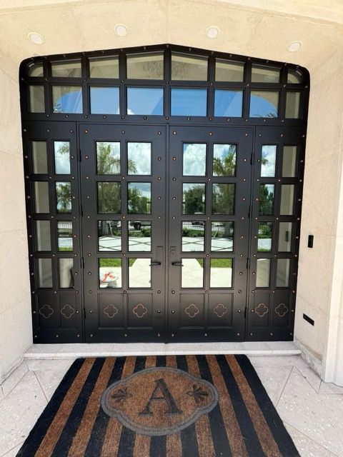 Brick house with a blue front door, matching shutters, and two flower pots on the porch.