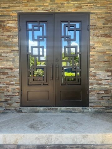 Brown wooden door with gold ornate window, next to a white pillar.
