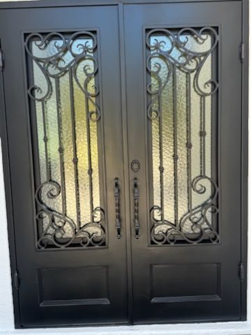 Person wearing a green glove wipes a window screen with a white cloth.