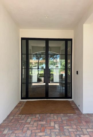 Man in hard hat and safety vest writing on a clipboard by a door, reflecting in the window.