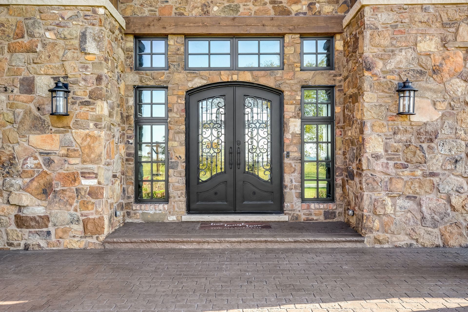 Stone facade entrance with double doors, sidelights, and overhead transom windows.