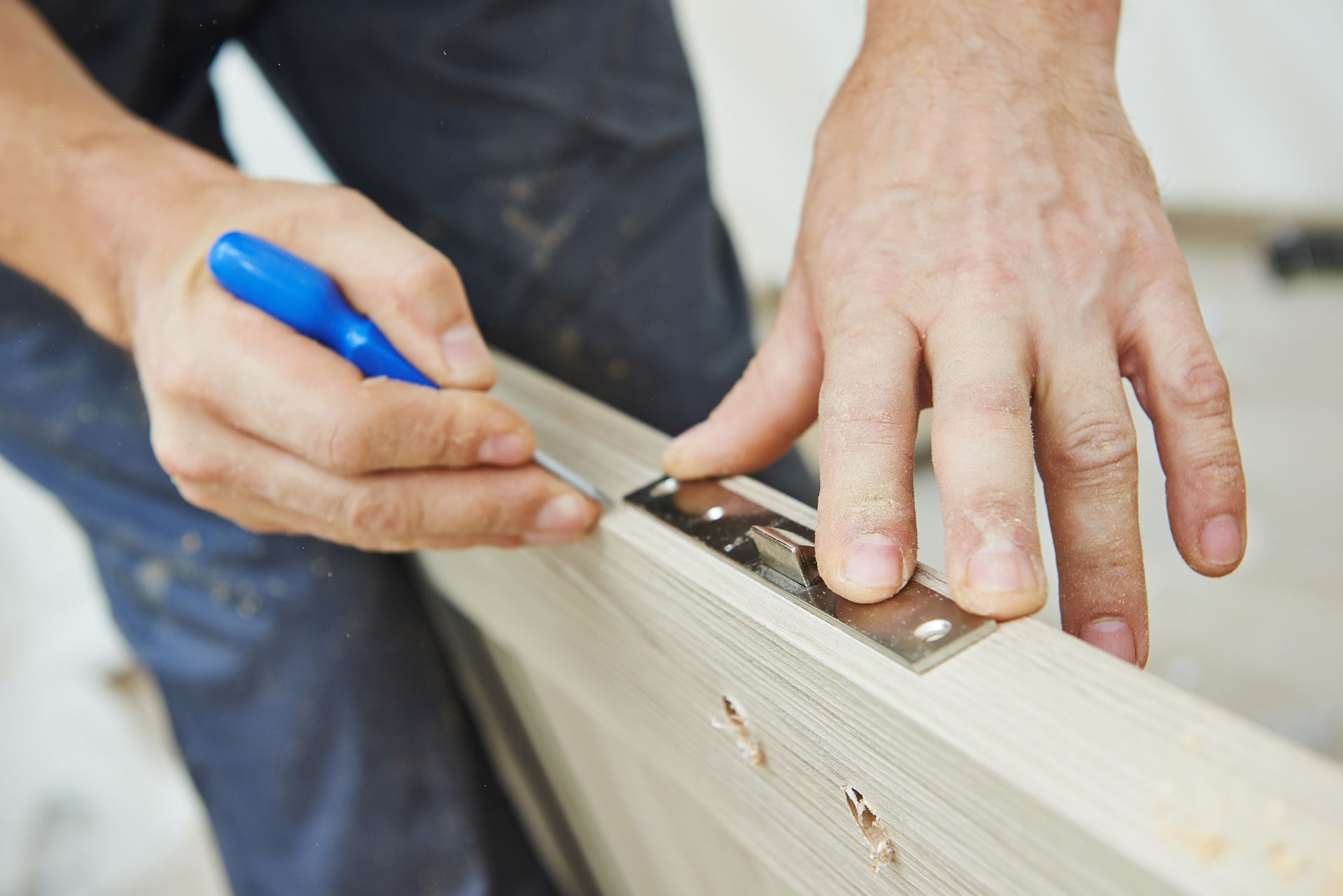 Person using a pencil to mark a door frame with a metal plate attached.