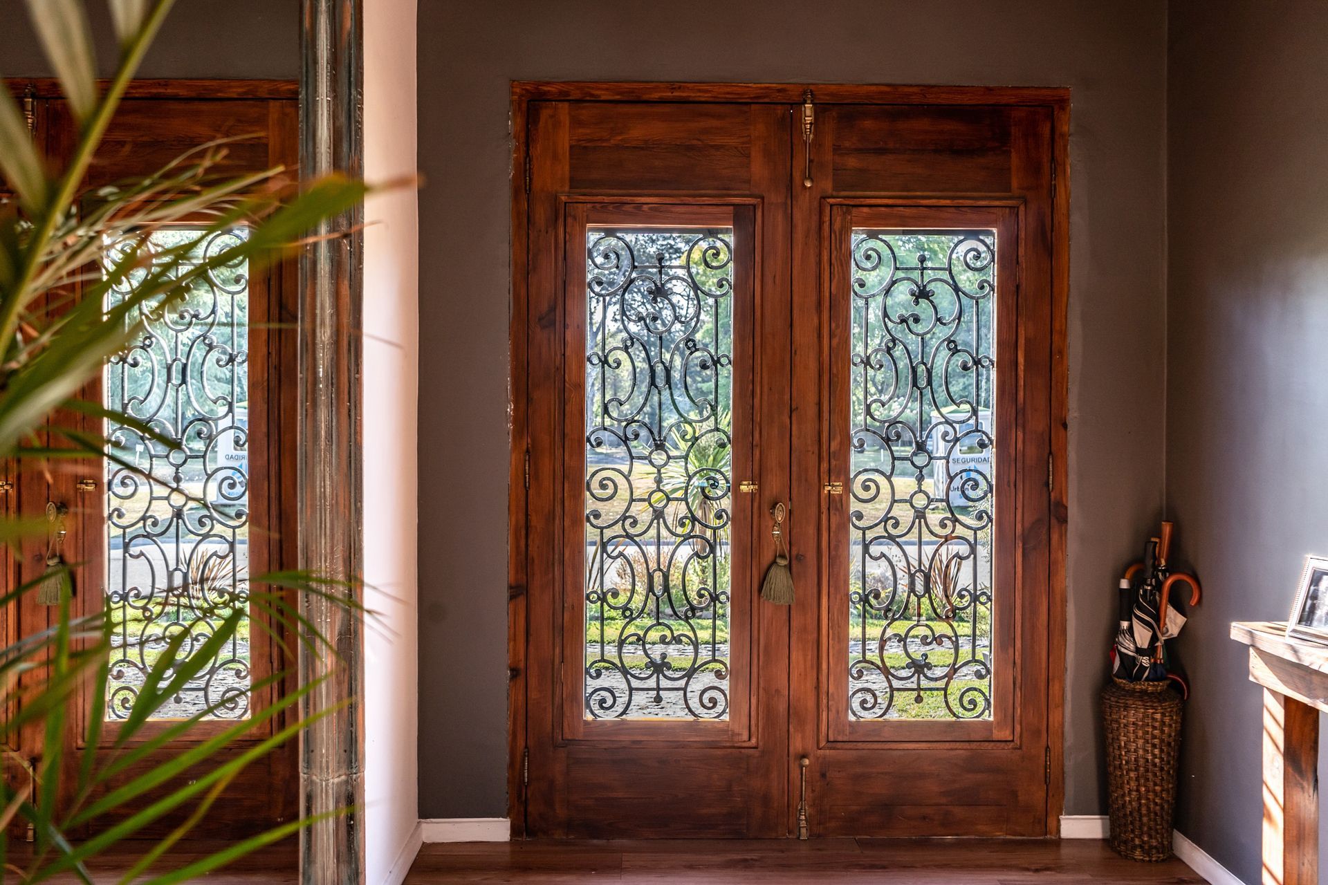 Wooden double doors with ornate glass panels, inside a house.