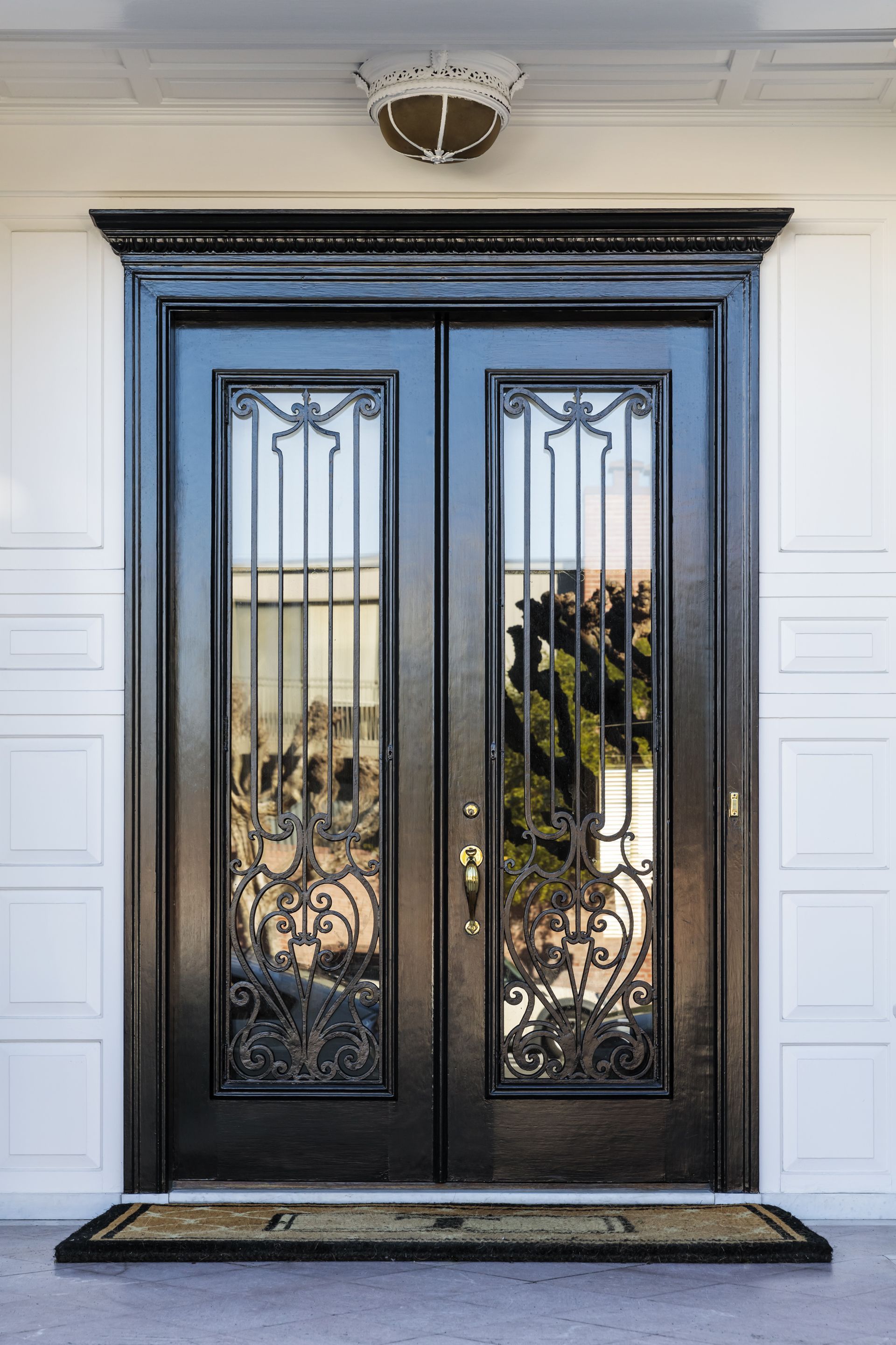 Black double doors with ornate ironwork and glass panels, set in a white exterior.