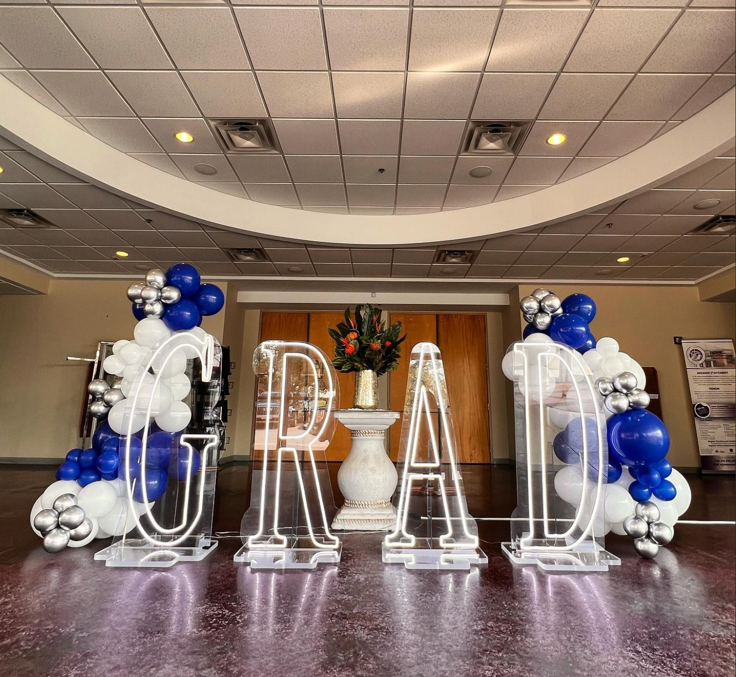 A room decorated with balloons and neon letters that spell out the word grad