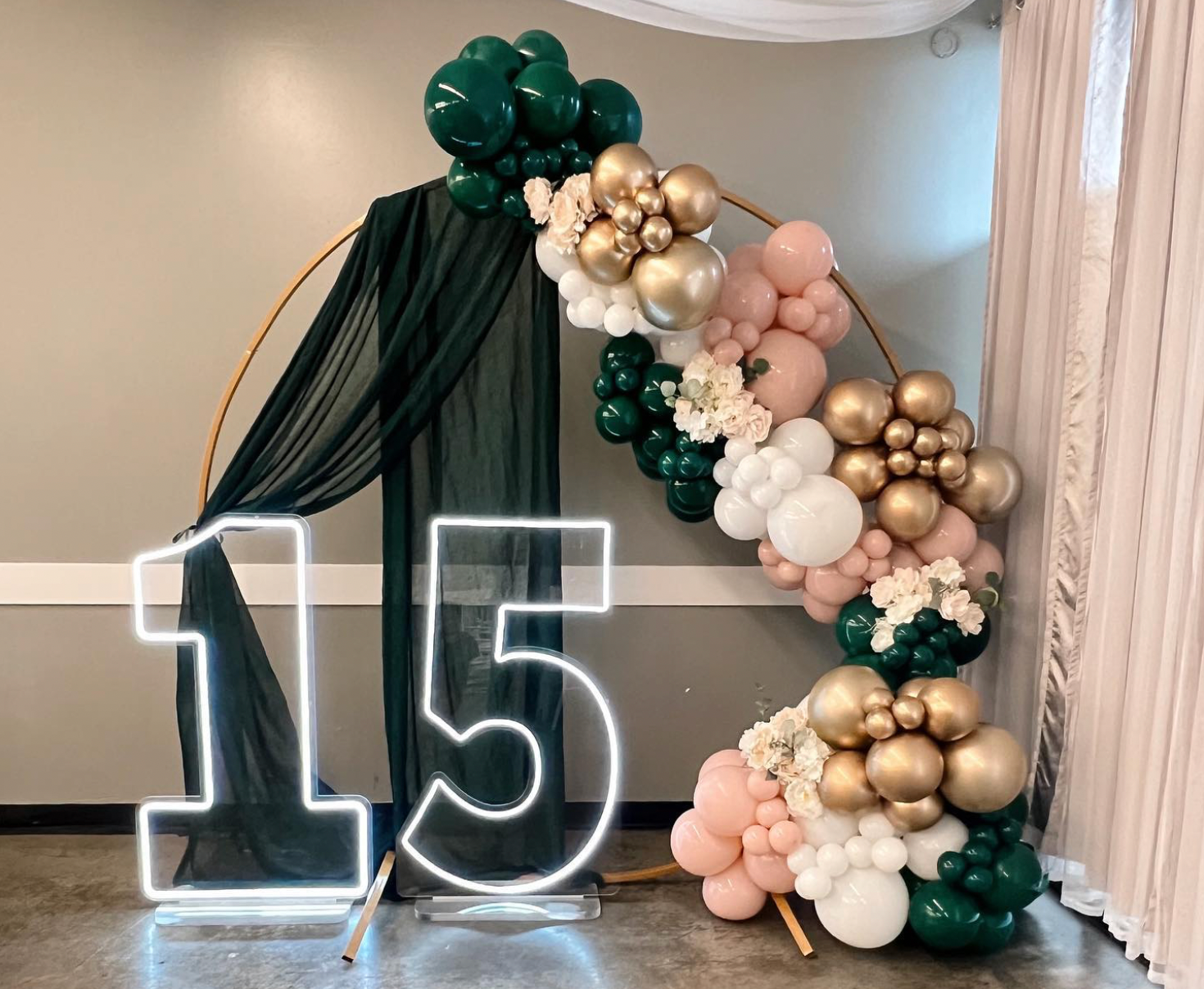 A room decorated with balloons and a neon sign that says 15.