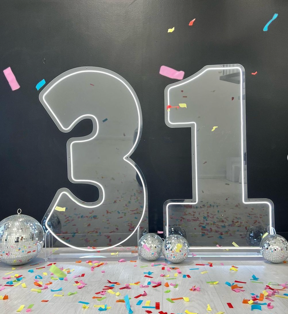 The number 31 is surrounded by disco balls and confetti