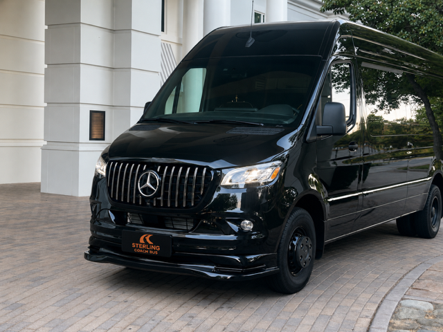 Black Mercedes-Benz van parked by a building entrance under a covered driveway.