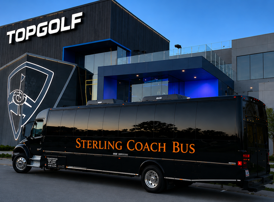 Black Sterling Coach Bus parked outside Topgolf at dusk, with blue-lit building behind it