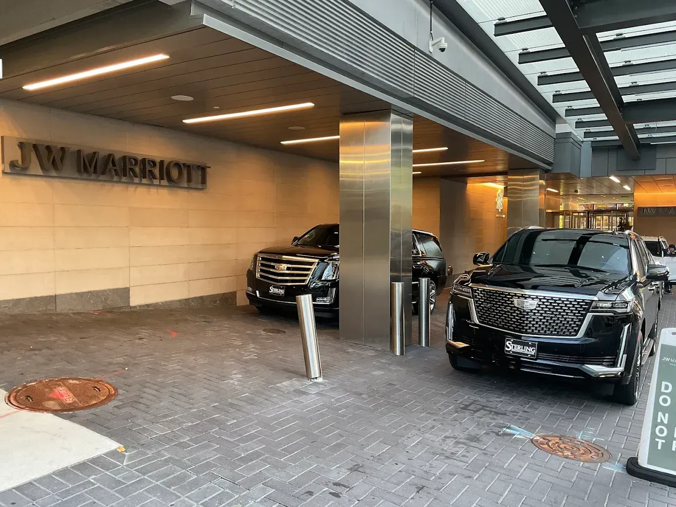 Covered hotel entrance with two black SUVs parked under an overhang.