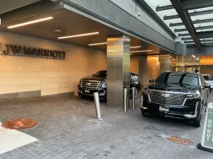 Covered hotel entrance with two black SUVs parked under an overhang.