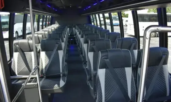 Empty modern bus interior with rows of gray seats and blue overhead lights