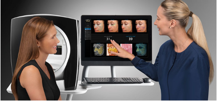 A woman is talking to another woman in front of a computer screen.