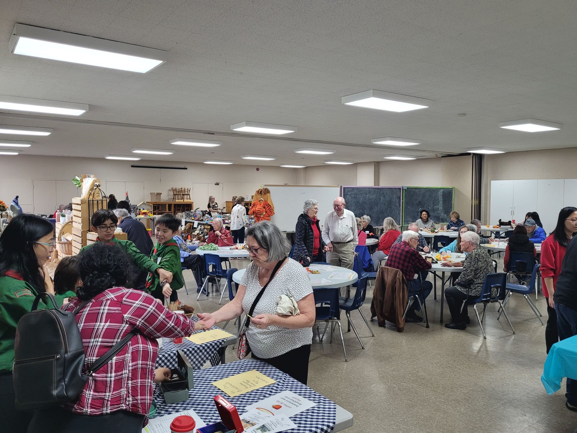 a group of people are standing around tables in a large room .