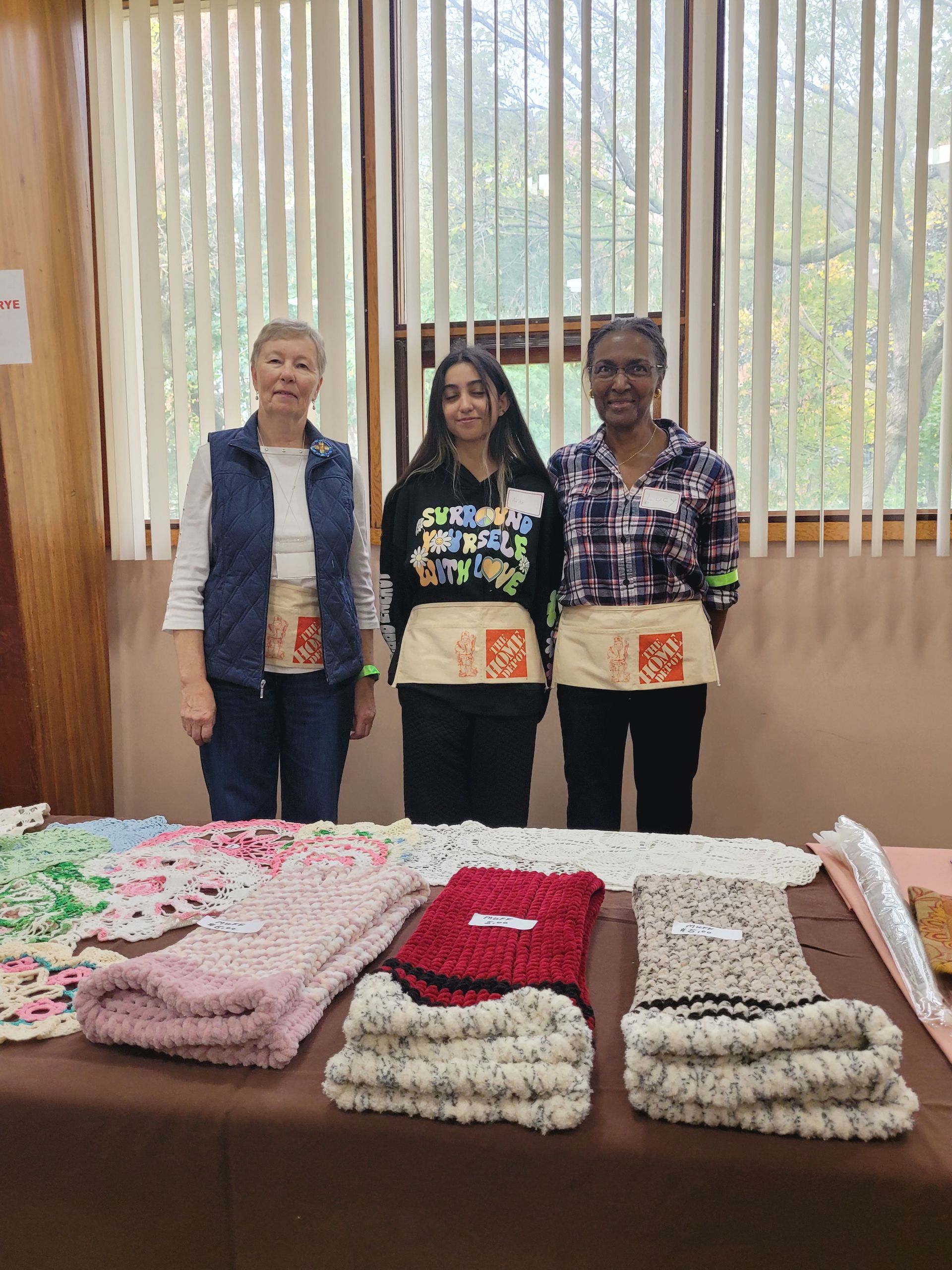three women are standing in front of a table with blankets on it .