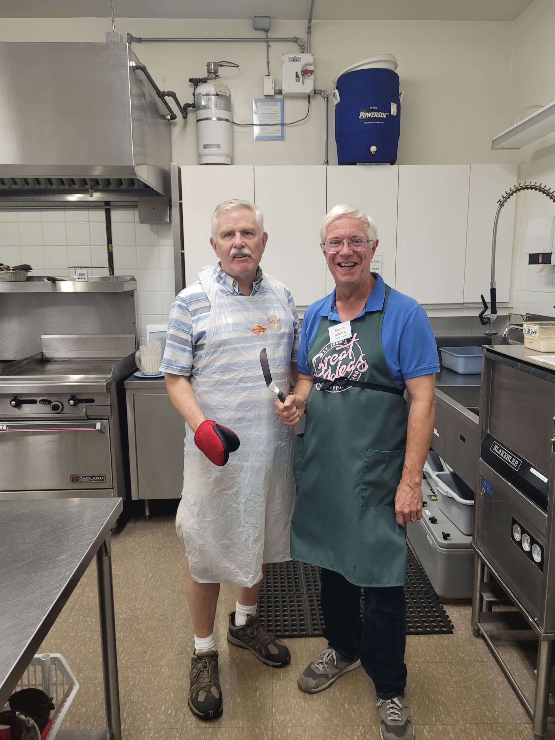 two men in aprons are standing in a kitchen