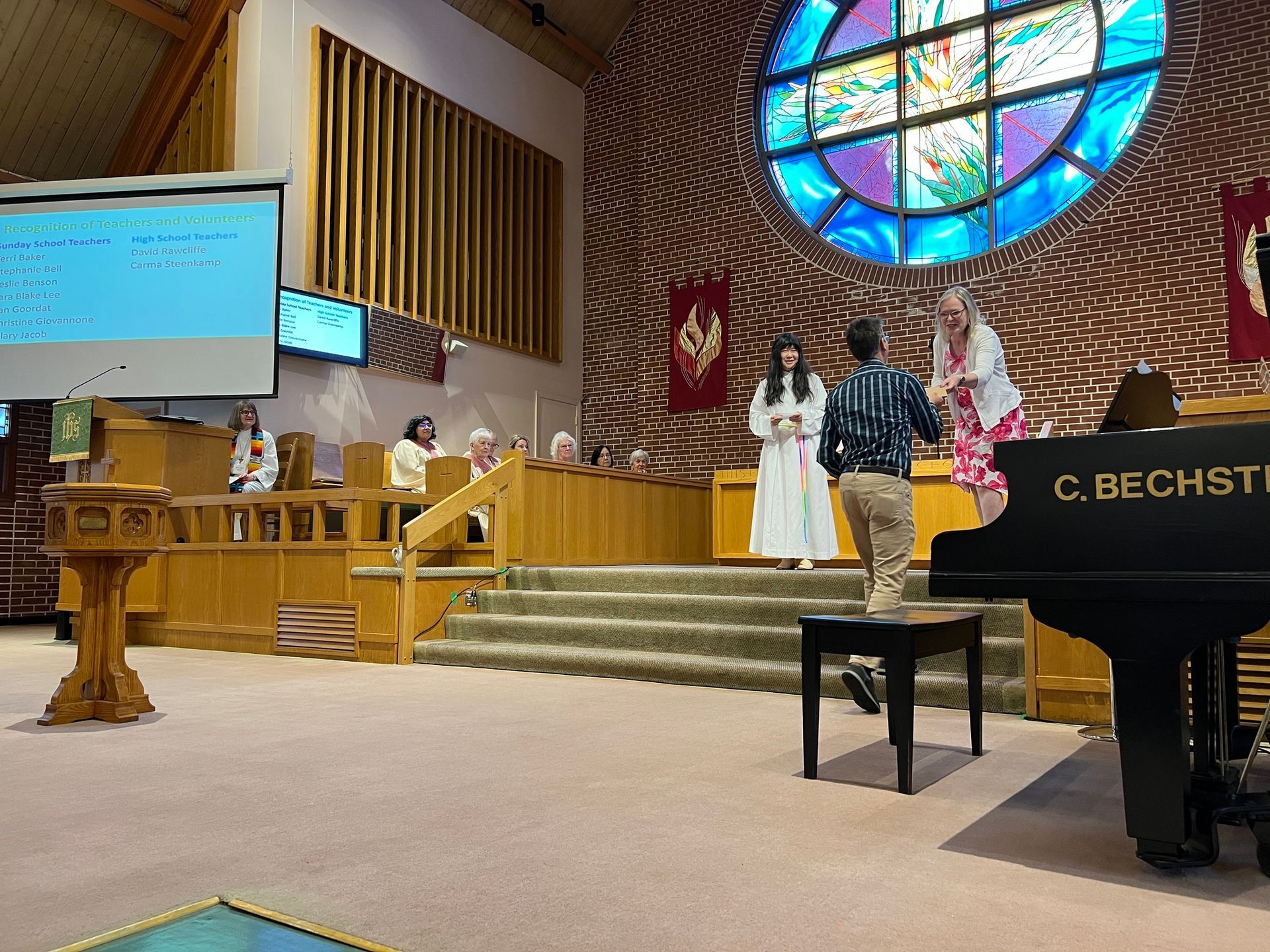 a group of people are standing in a church in front of a stained glass window .