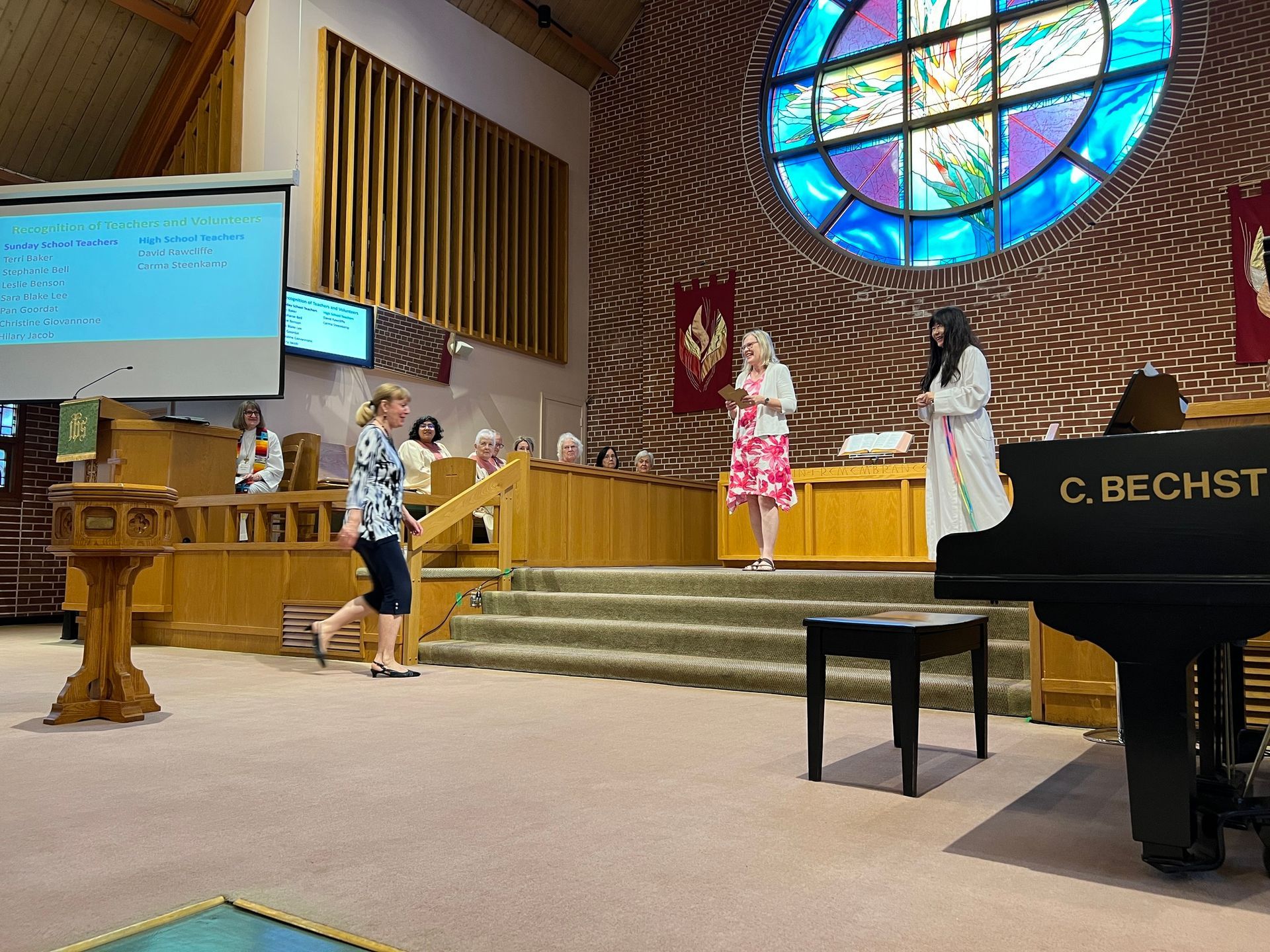 two women are standing in front of a piano in a church .