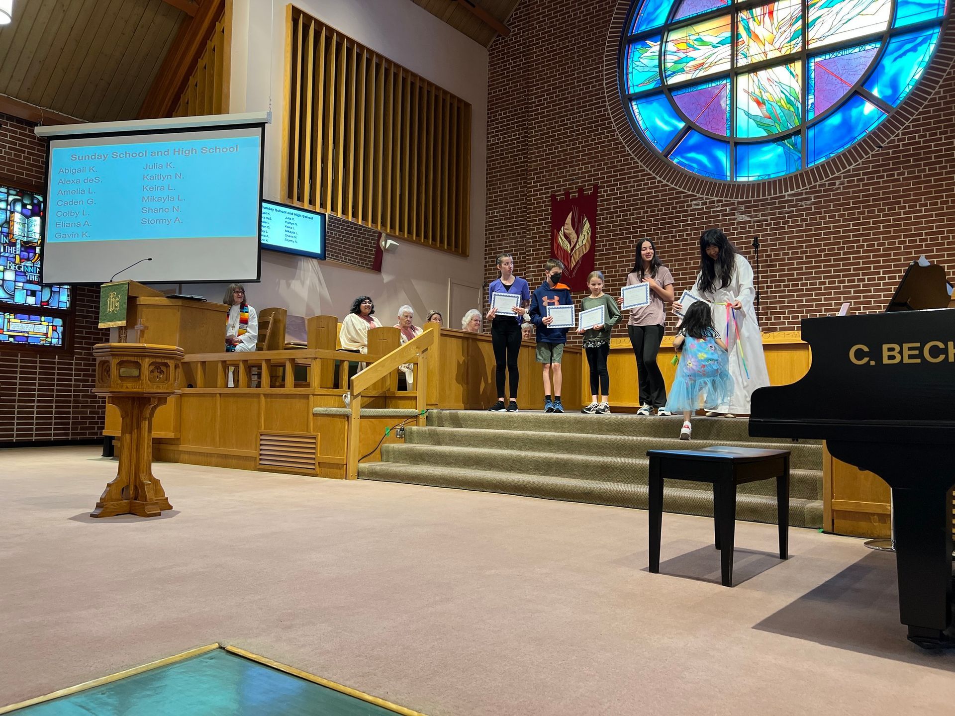 a group of people are standing in front of a piano in a church .