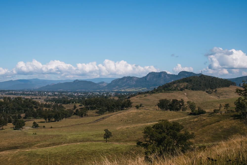 A View Of A Grassy Hillside With Mountains In The Background On A Sunny Day β Bulley Roof Restoration, Painting & Pressure Cleaning in Gloucester, NSW