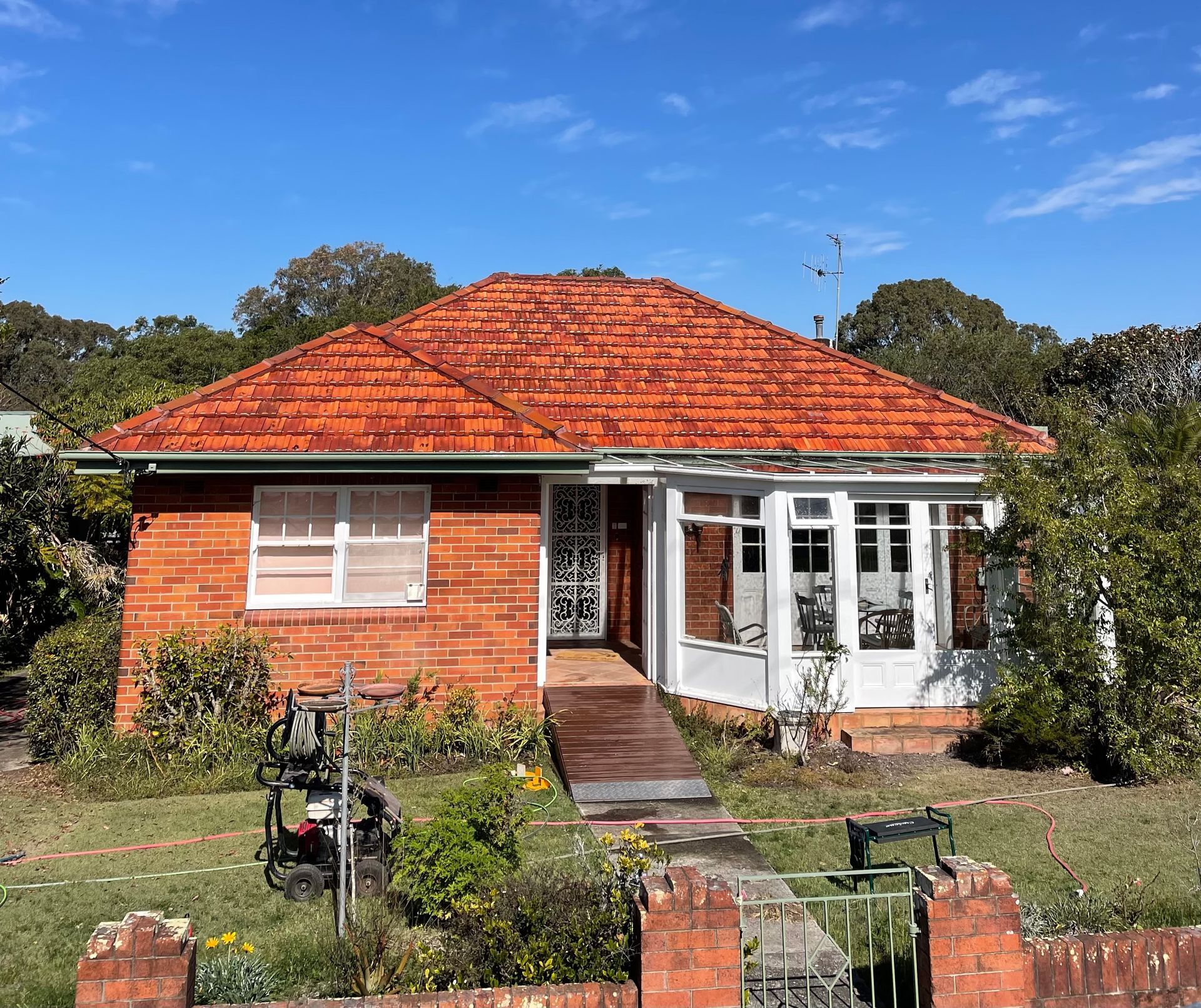 A Brick House With A Water Tank In Front Of It — Bulley Roof Restoration, Painting & Pressure Cleaning in Port Macquarie, NSW