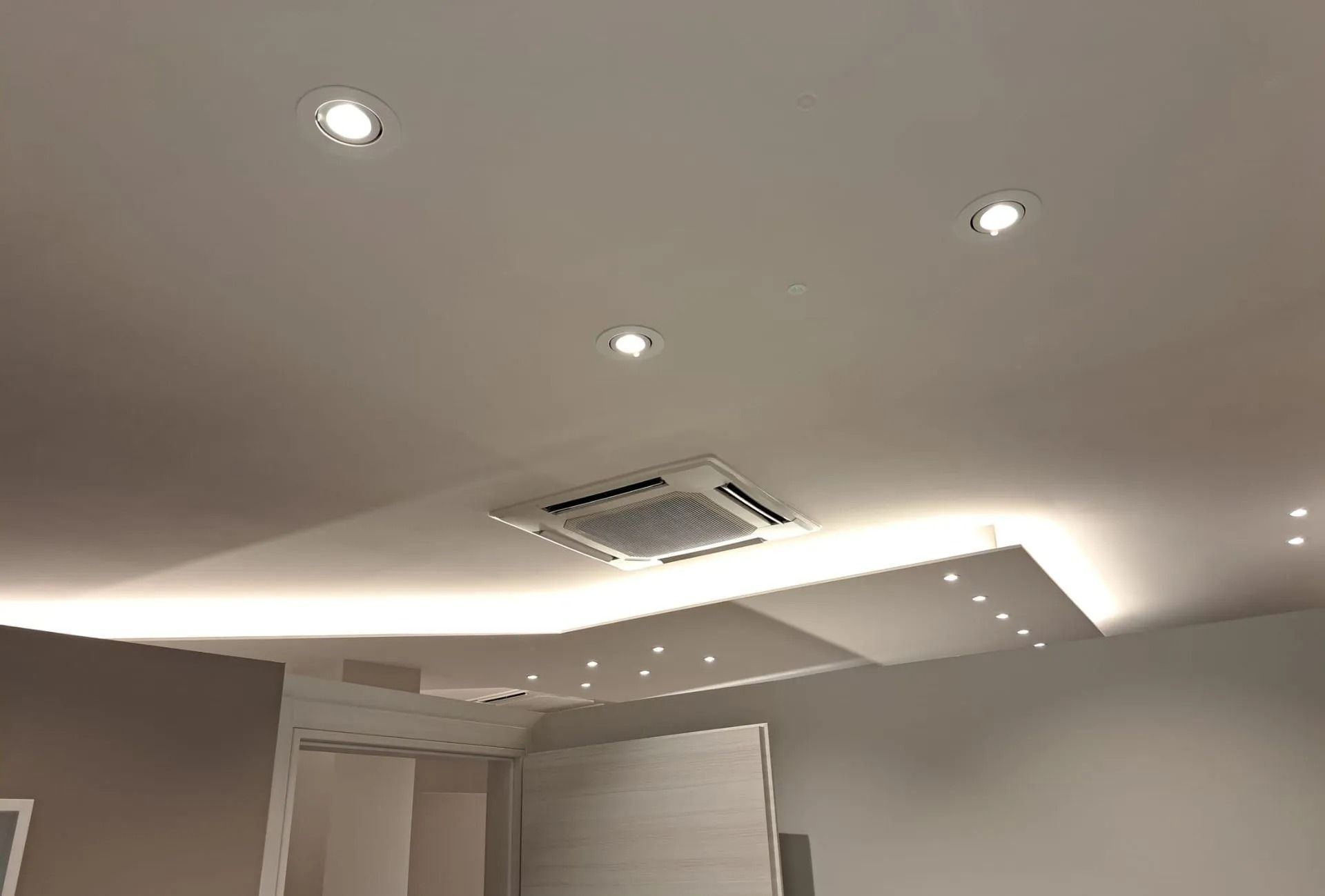 Soffitto con luci da incasso, unità di aria condizionata e apparecchi di illuminazione integrati.