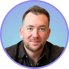 Smiling man with a short beard in a black shirt, set against a light blue gradient background.
