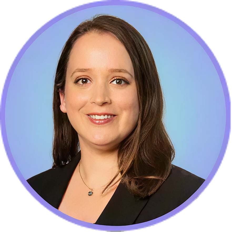 Woman with brown hair smiling, wearing a black blazer and necklace, against a blue background.
