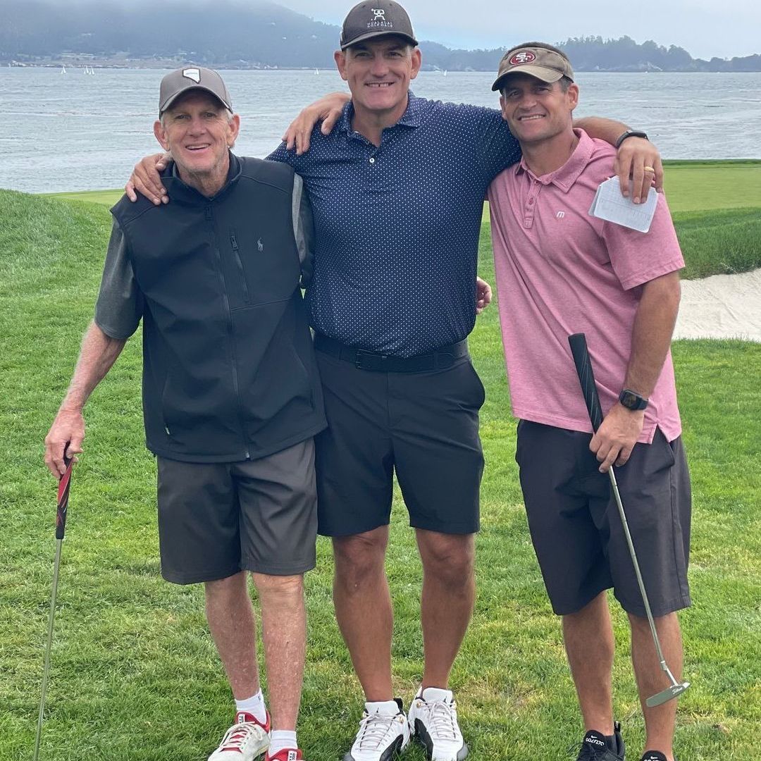 A man and a woman are posing for a picture with the ocean in the background
