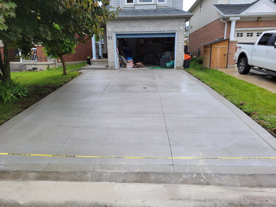 A concrete driveway leading to a house with a truck parked in front of it.