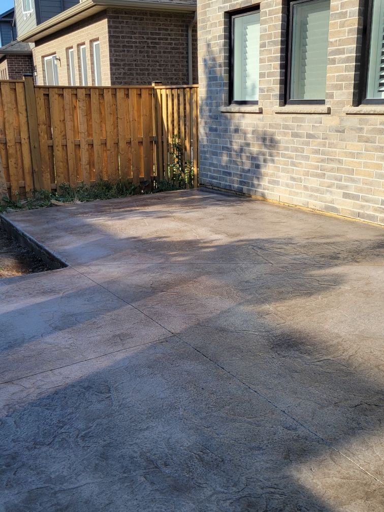 A brick house with a wooden fence and a concrete driveway in front of it.