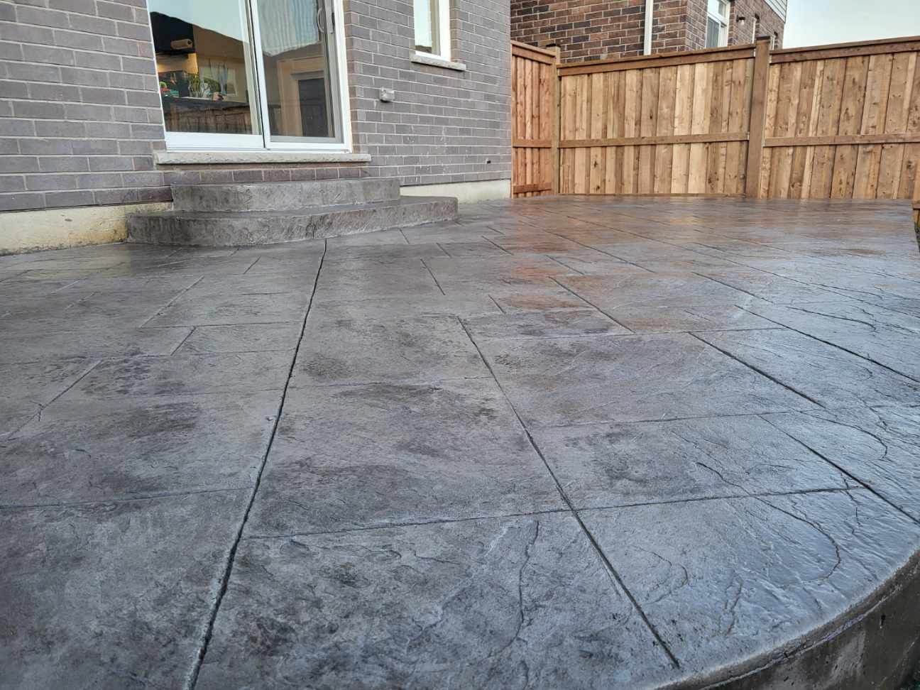 A concrete patio with a wooden fence in the background.