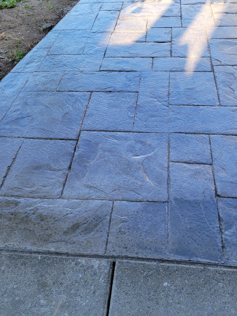 A close up of a stamped concrete brick walkway with a shadow on it.