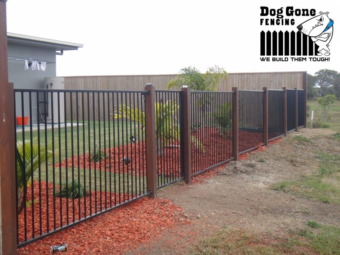 A Black Metal Fence With Wooden Posts Is In Front Of A House — Dog Gone Fencing in Paget, QLD
