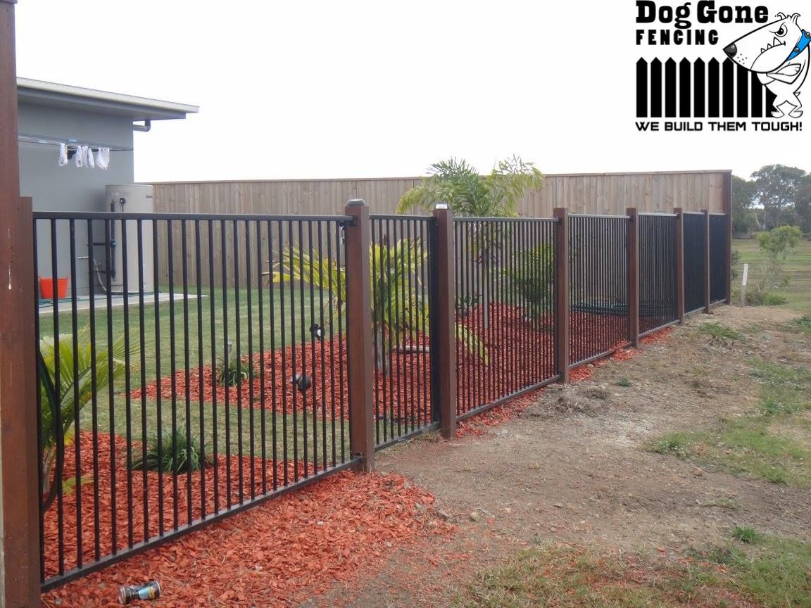 A Black Metal Fence With Wooden Posts In Front Of A House — Dog Gone Fencing in Paget, QLD