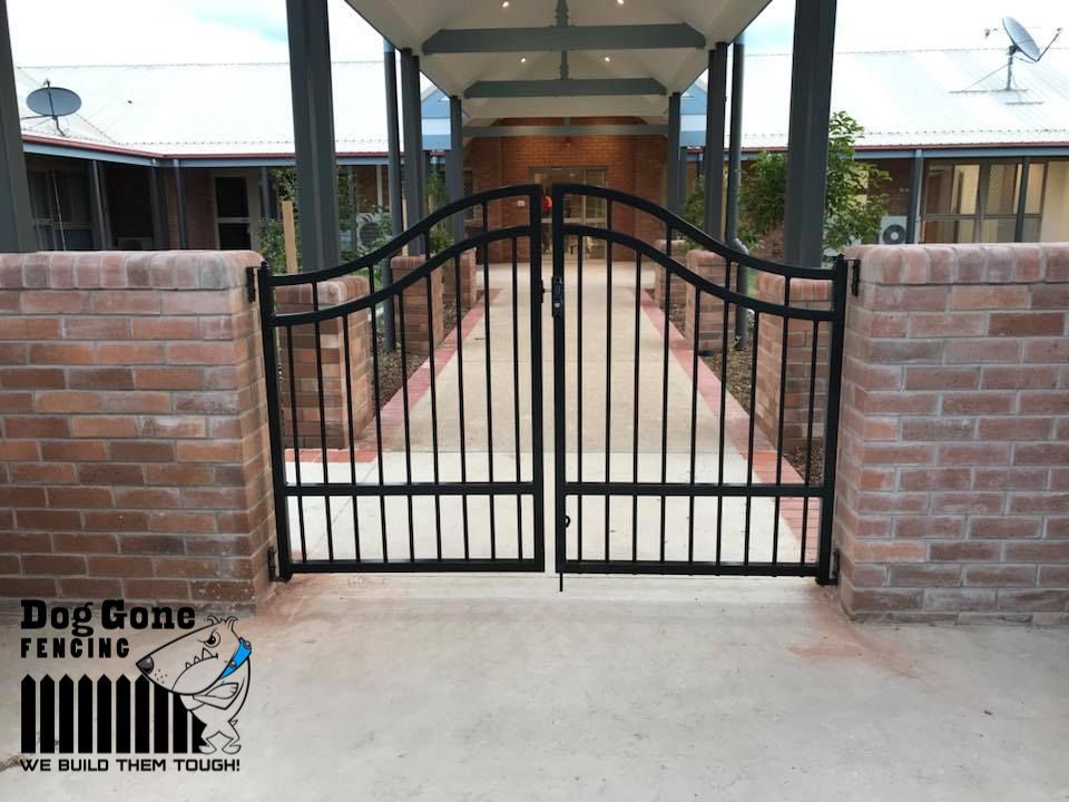 A Brick Wall With A Black Gate In Front Of It That Says Keep Gone Welding — Dog Gone Fencing in Paget, QLD