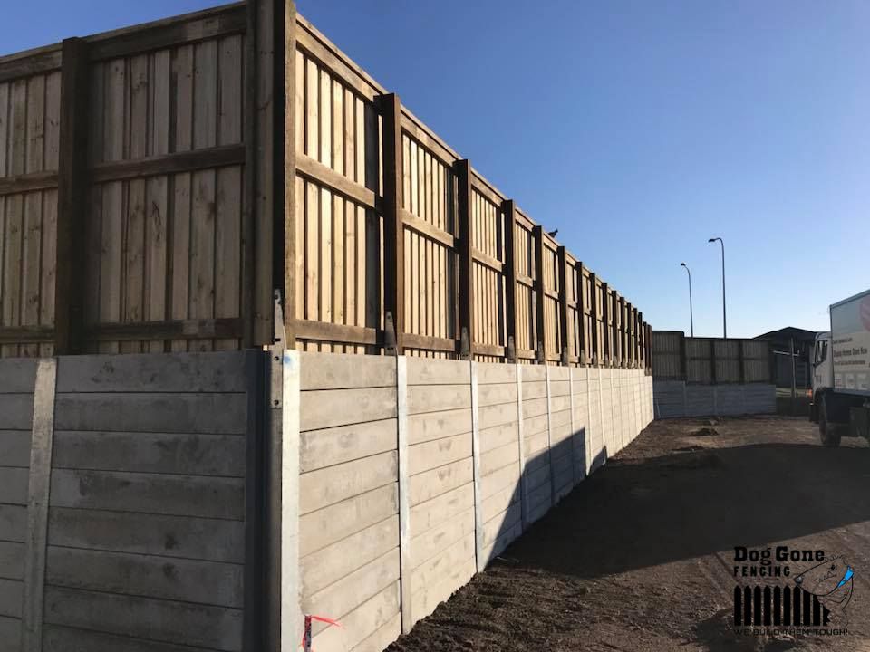 A Large Concrete Wall With Wooden Fences Surrounding It — Dog Gone Fencing in Paget, QLD