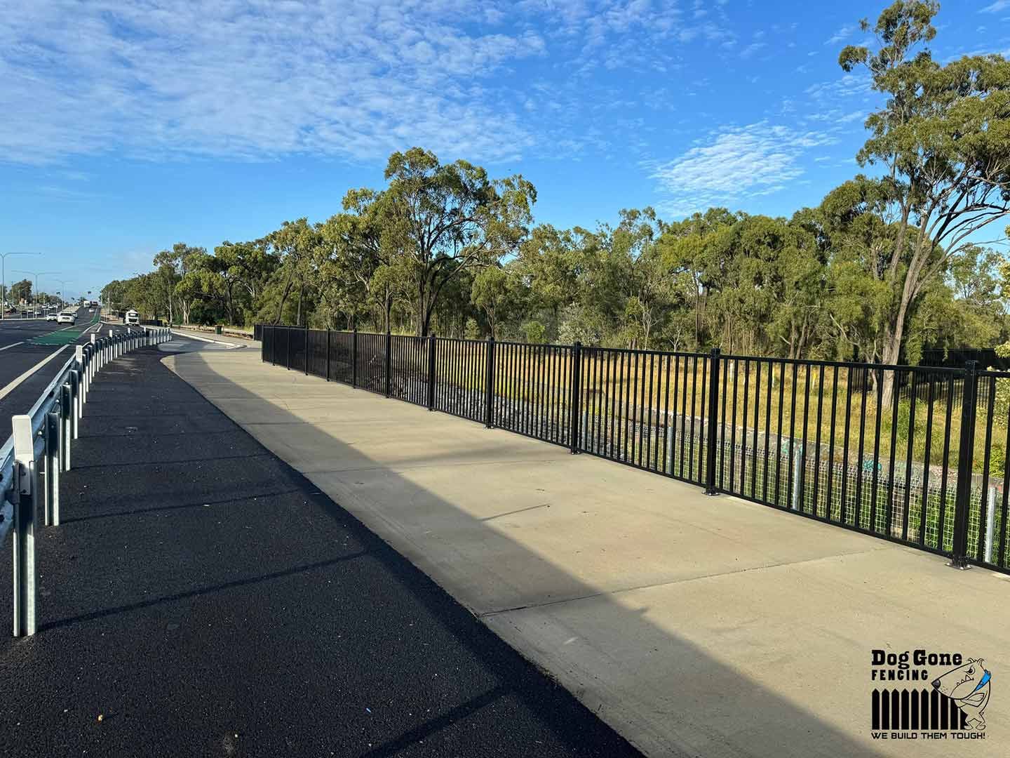 A Fence Along A Sidewalk With Trees In The Background — Dog Gone Fencing in Sunshine Coast, QLD