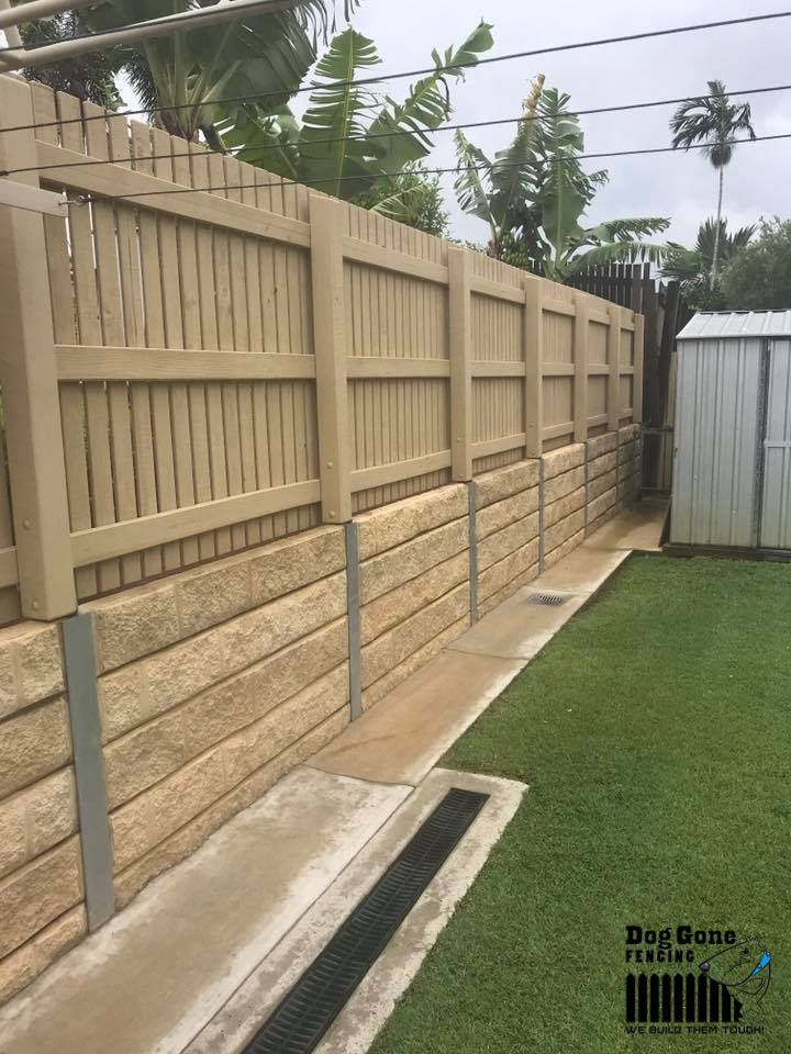 A Wooden Fence Is Sitting Next To A Concrete Wall In A Backyard — Dog Gone Fencing in Paget, QLD