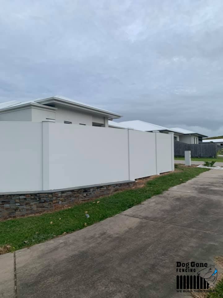 A White Fence Surrounds A House In A Residential Area — Dog Gone Fencing in Paget, QLD