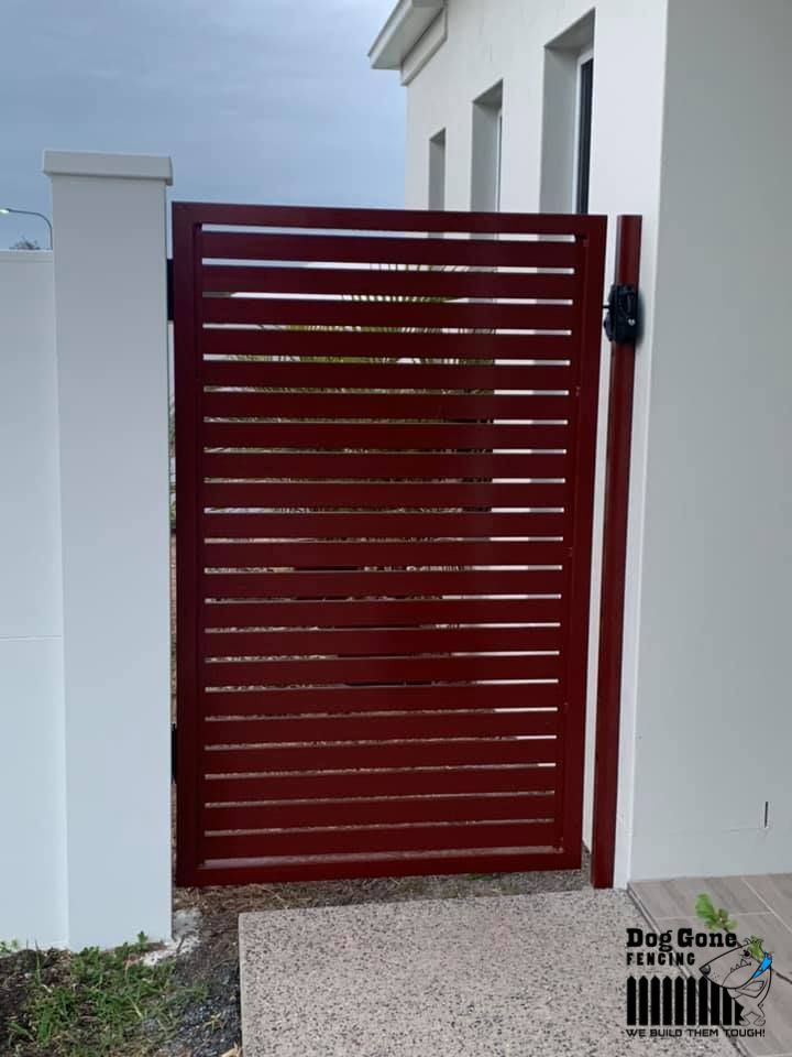 A Red Gate Is In Front Of A White Building — Dog Gone Fencing in Paget, QLD