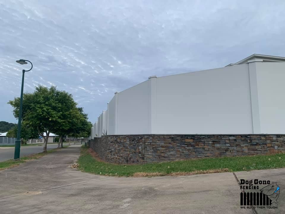 A Large White Building With A Stone Wall And A Street Light In Front Of It — Dog Gone Fencing in Paget, QLD